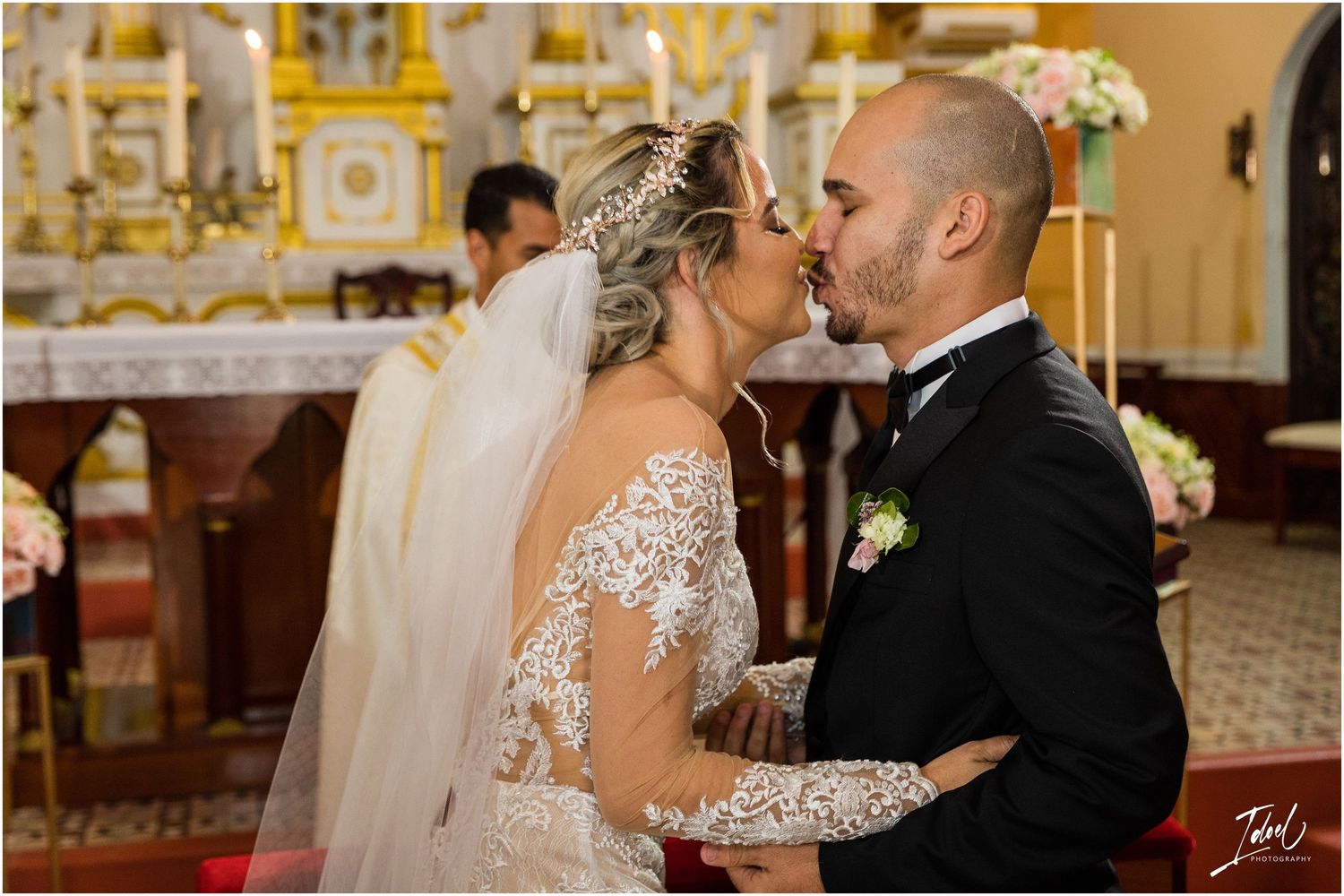 Intimate moment during church wedding ceremony with ornate altar background.