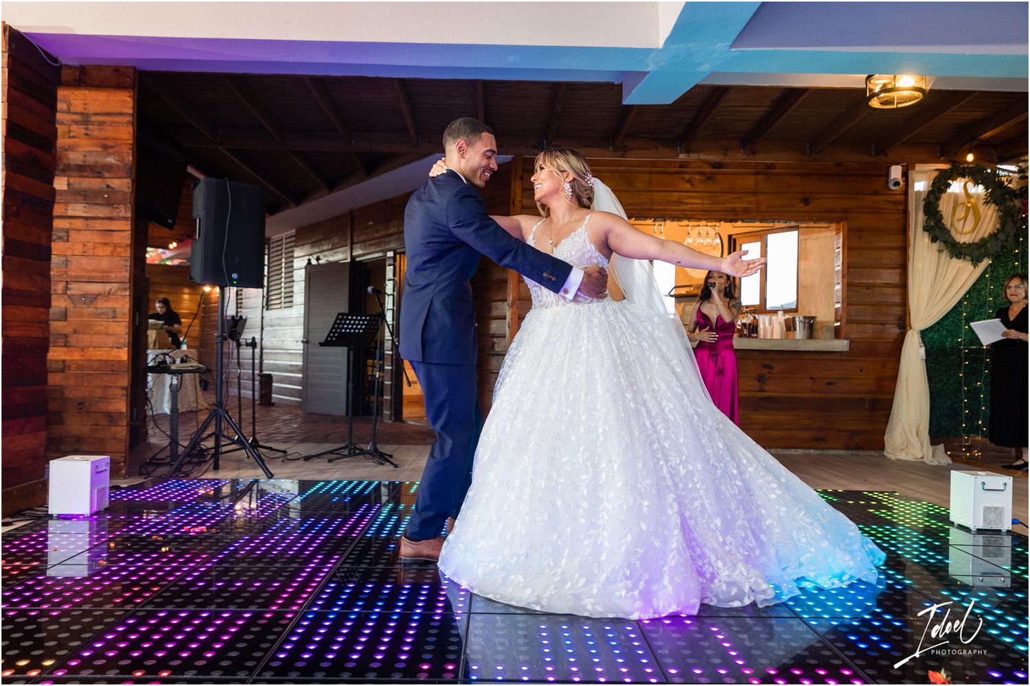 Wedding dance captured on illuminated LED floor with purple lighting in rustic venue.