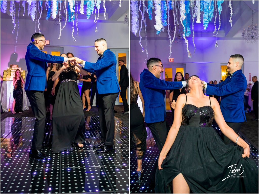 Fun dance party scene with people in blue and black attire dancing under purple hanging decorations on a light-up floor.