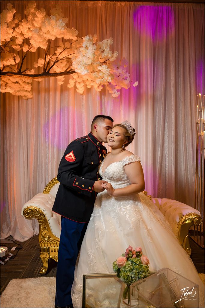 Wedding portrait with elegant floral backdrop and ornate gold furniture.