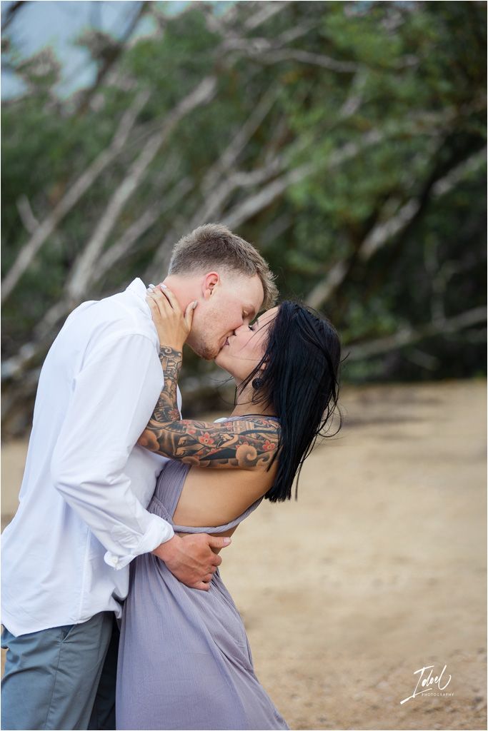 Intimate moment between couple with tattoos embracing outdoors.