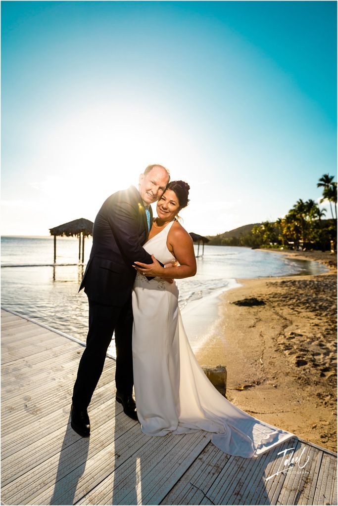 A sunset beach wedding portrait on a wooden boardwalk with palm trees and ocean views.