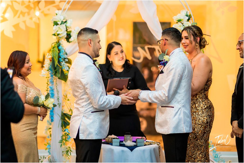 A wedding ceremony taking place indoors with yellow walls and floral decorations as people gather for the special moment.