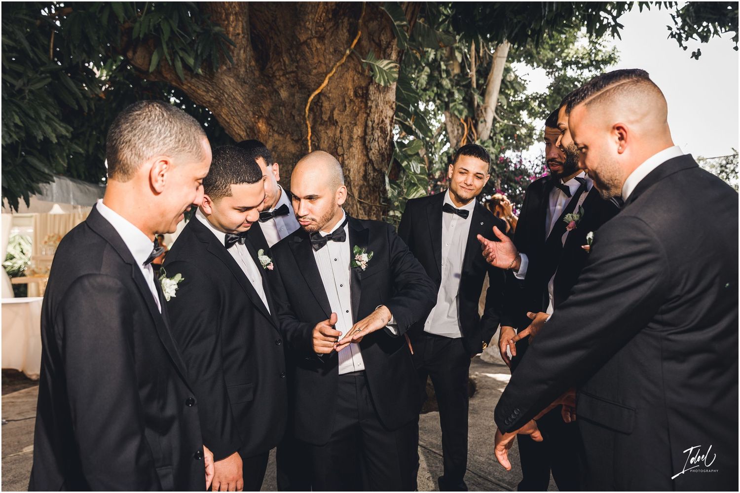 Groomsmen gather in formal attire sharing jokes and laughter during pre-wedding photos.