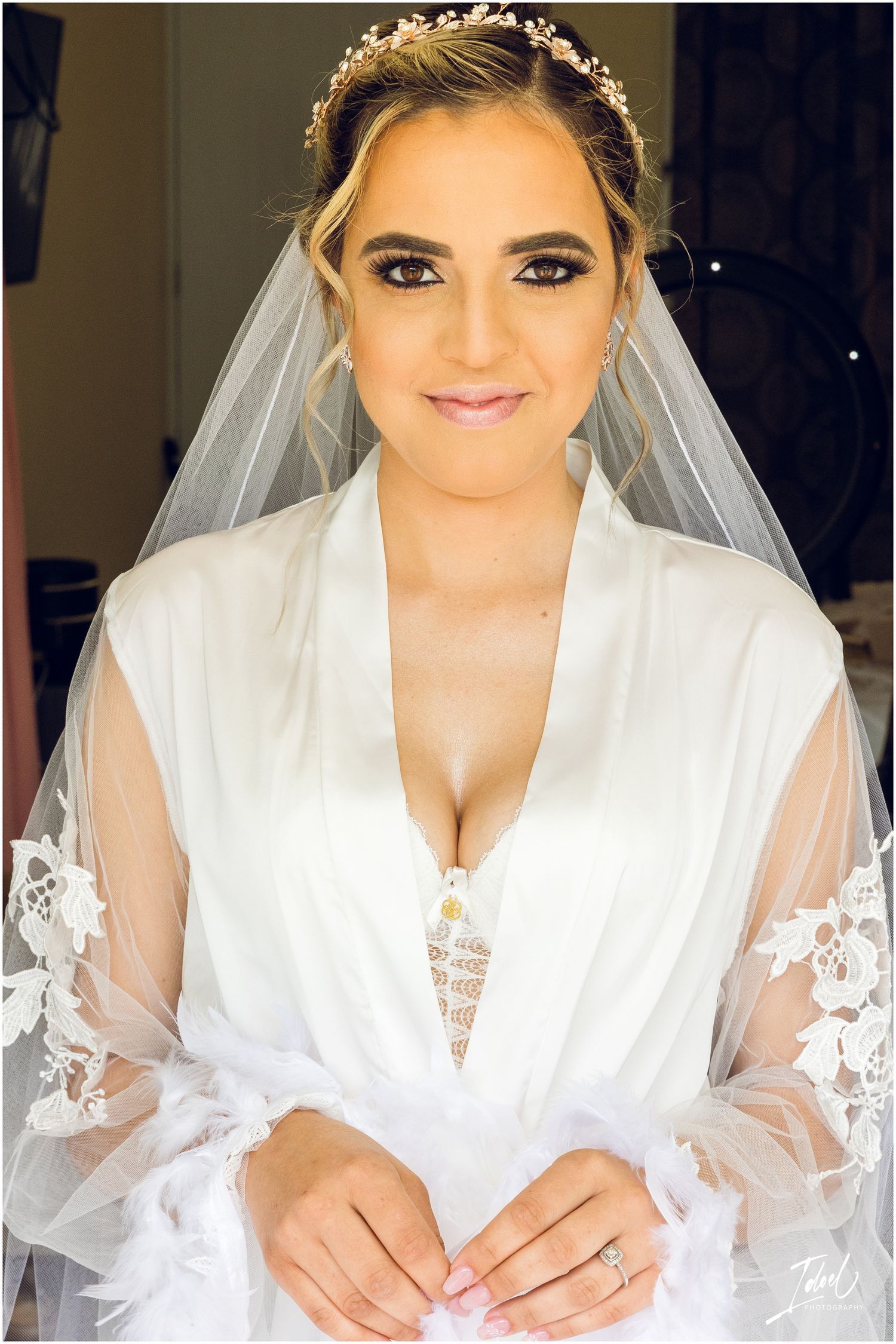 Close-up bridal portrait showcasing elegant makeup and crystal crown with attached veil.