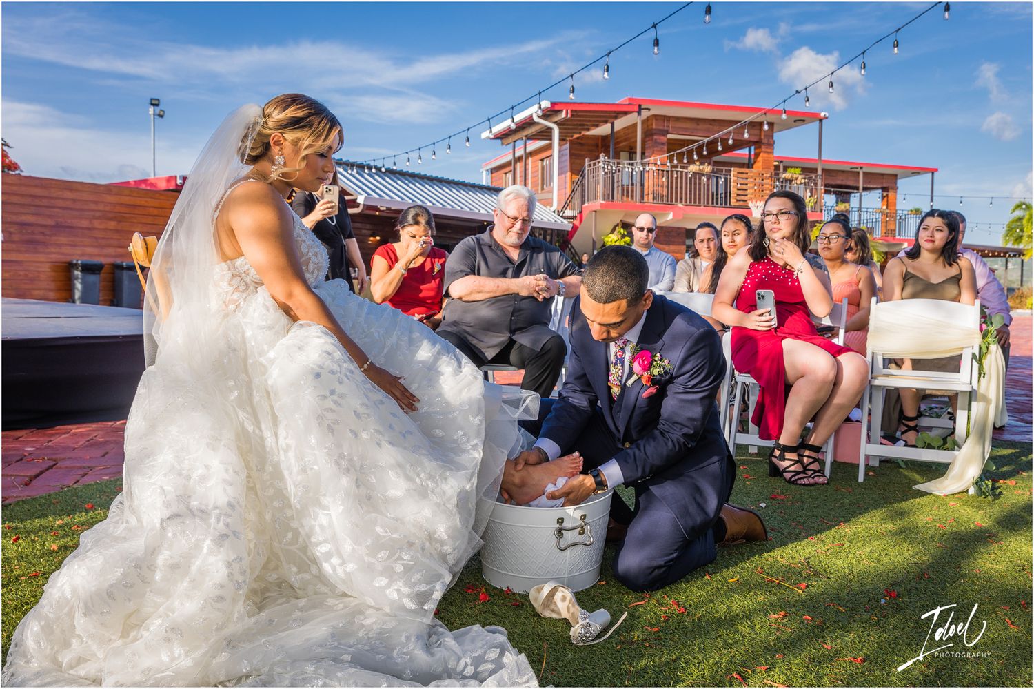 Playful moment during outdoor wedding reception with string lights and red decor.