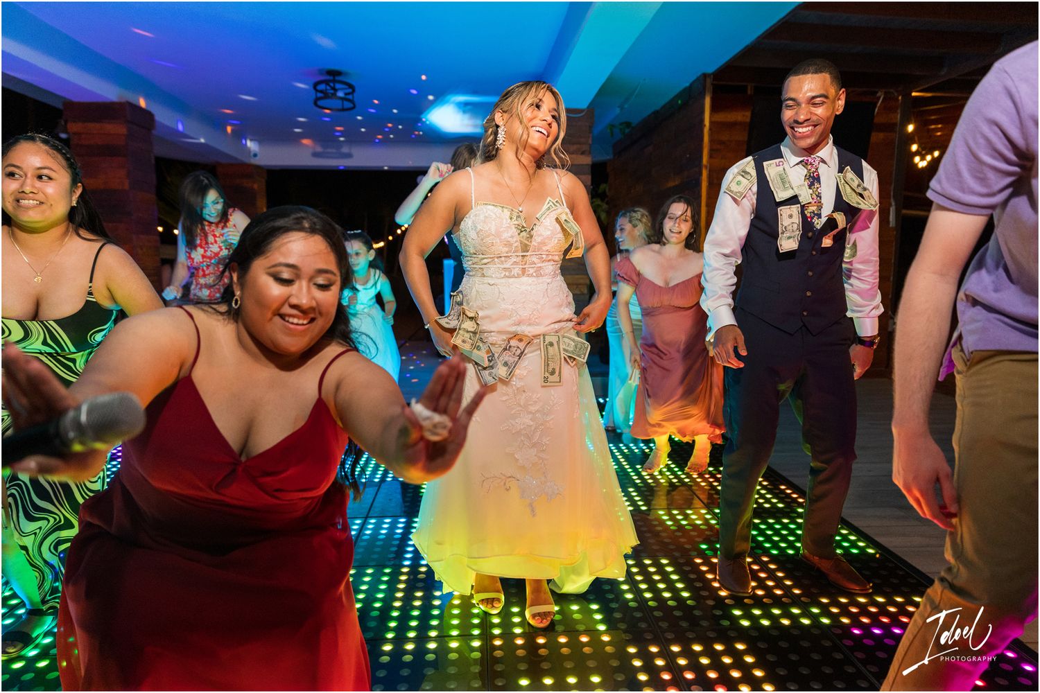 Wedding celebration with guests dancing on a vibrant LED floor under blue lighting.