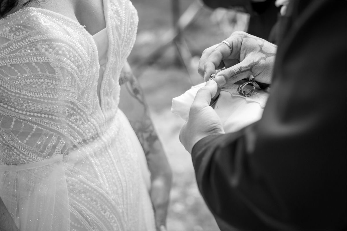 Close-up shot of hands adjusting details on an elegant white wedding dress.