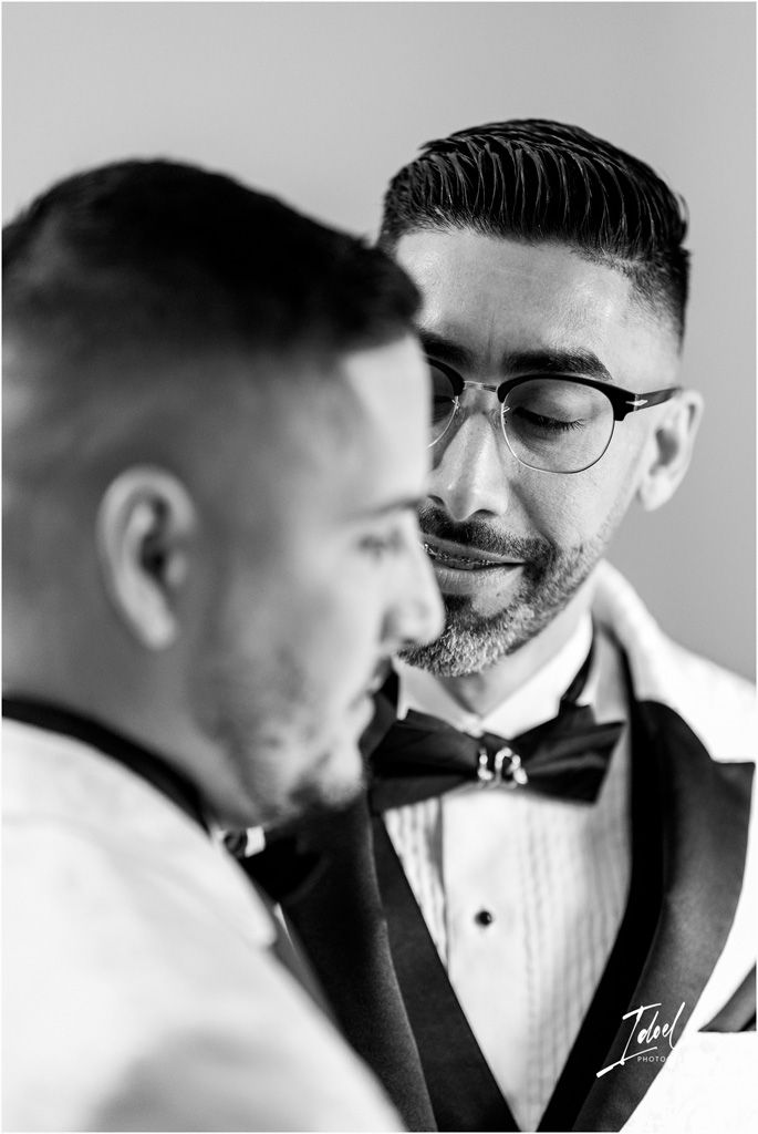 A black and white close-up photograph of two people in formal attire with bowties sharing an intimate moment.