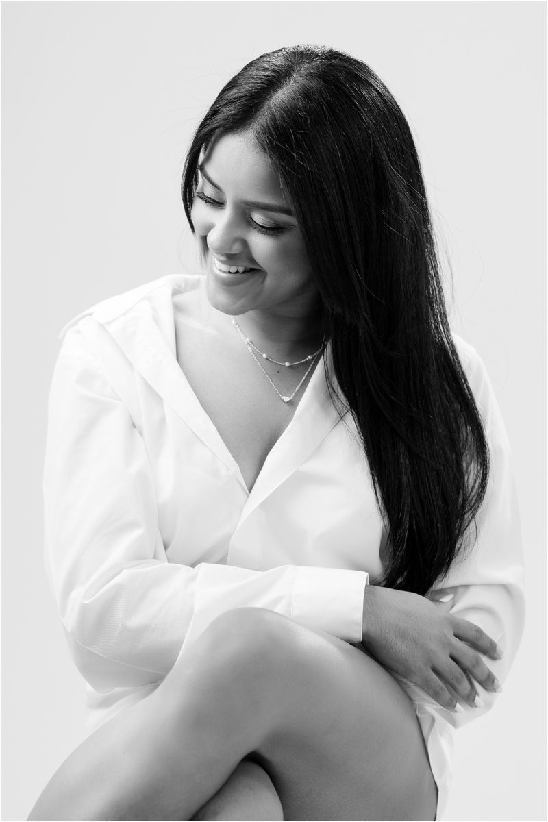 A black-haired woman in a white button-up shirt poses against a light background in a series of candid portraits.