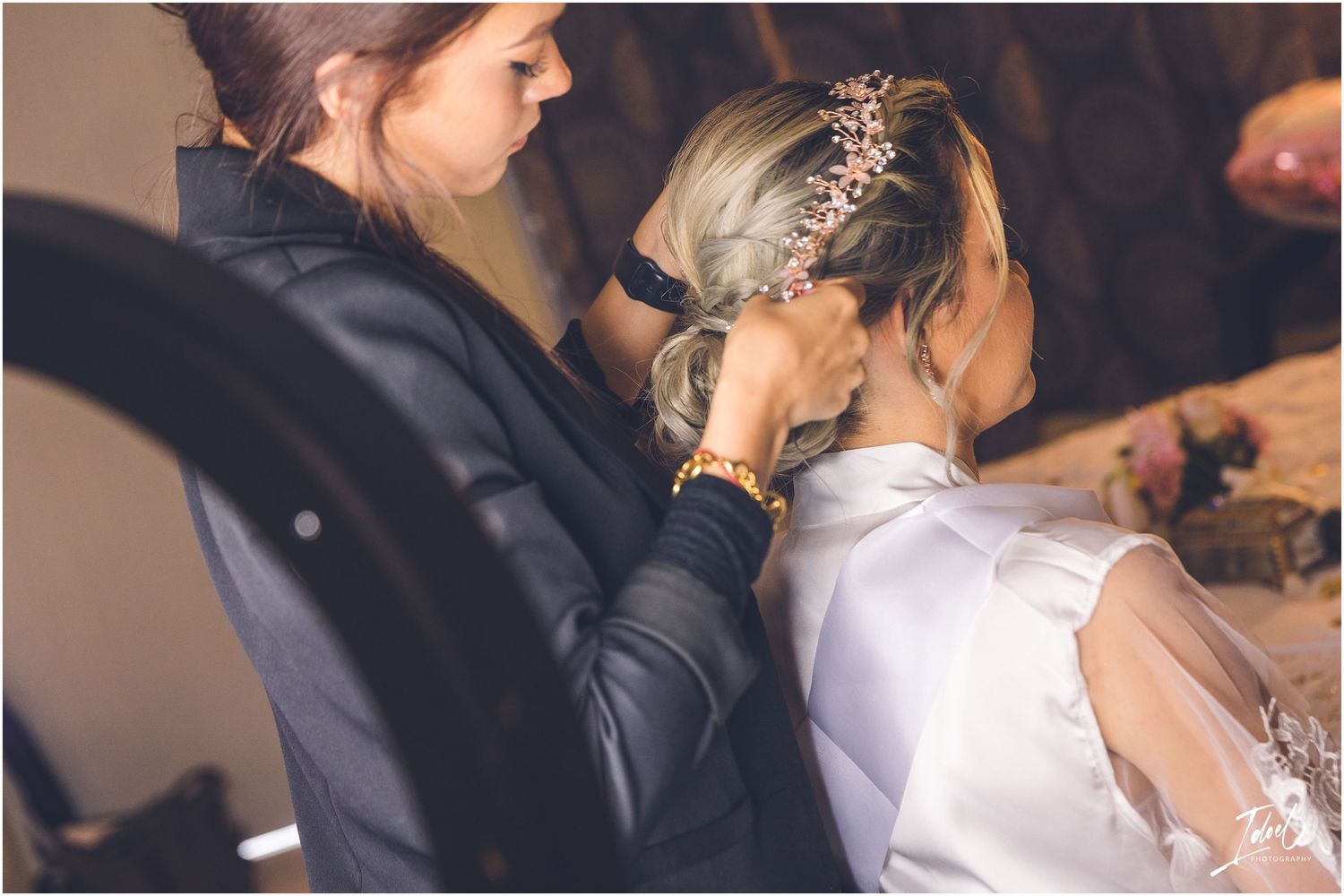 Wedding preparation scene with stylists working on bridal hair and makeup.