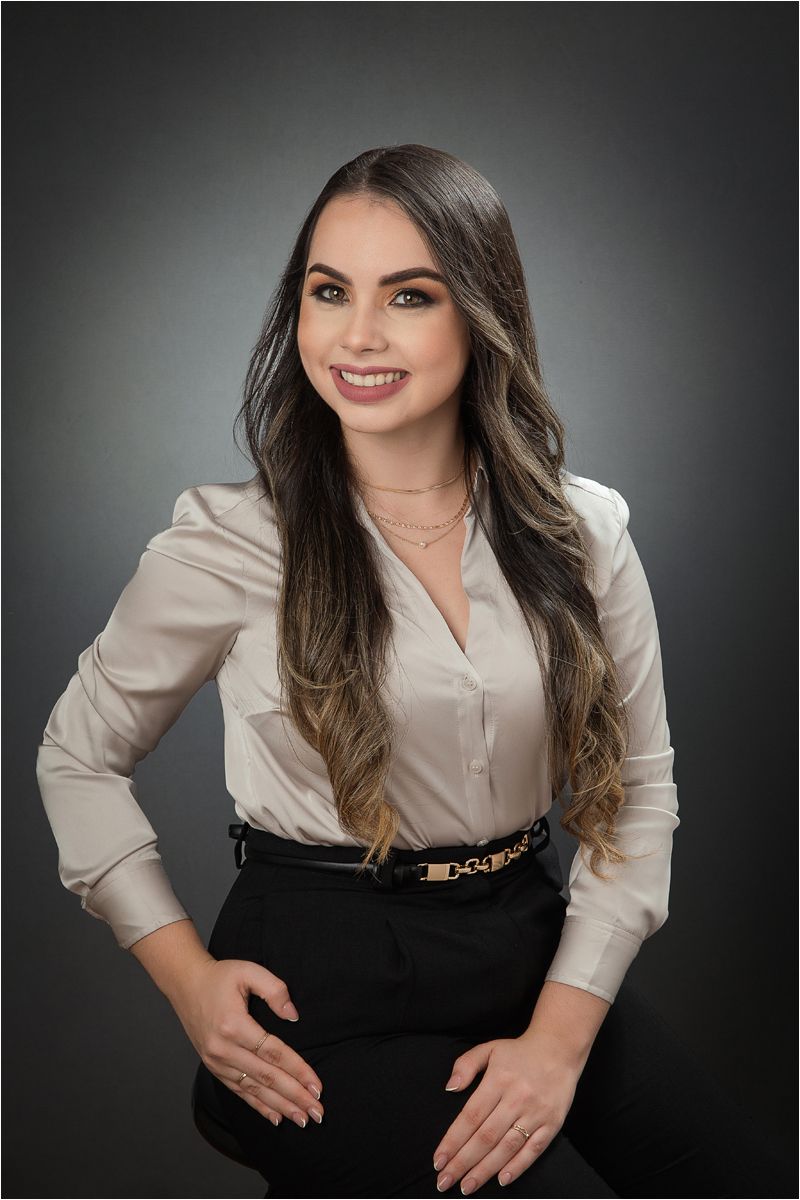 Professional studio portrait of someone wearing a white button-down shirt and black dress against dark background.