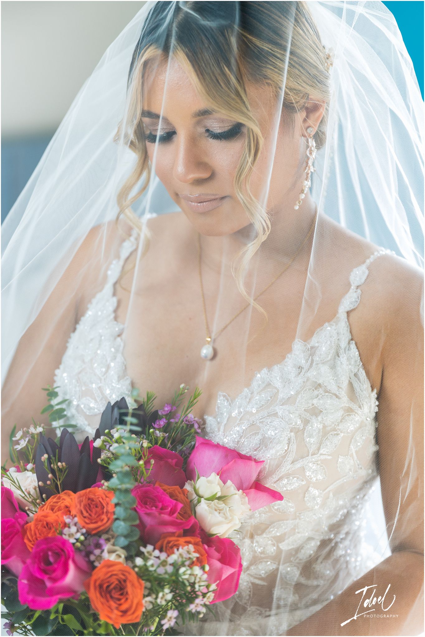 Romantic bridal portrait with soft lighting showcasing lace gown and pink floral bouquet.