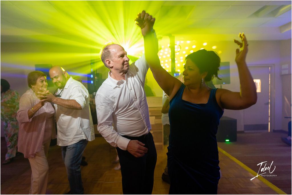 Energetic dancing at wedding reception with vibrant yellow lighting effects.
