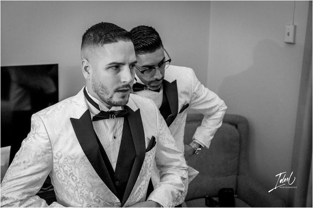 Black and white photo showing two people in formal tuxedos getting ready for an elegant event.