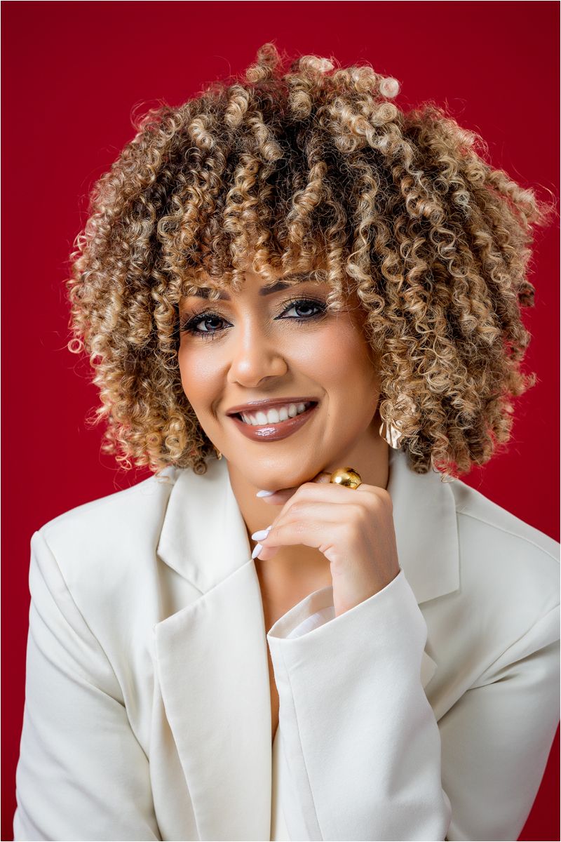 Portrait series against red backdrop showing expressive poses in white blazer with curly blonde hair.