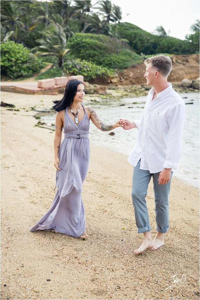 Couple sharing playful moment on tropical beach with palm trees.