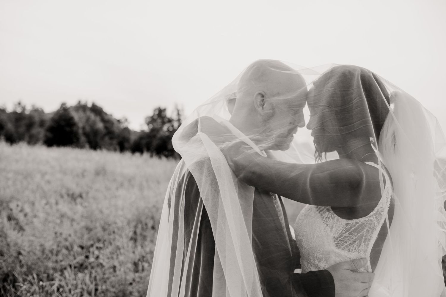 An intimate black and white wedding portrait showing a tender moment between newlyweds.