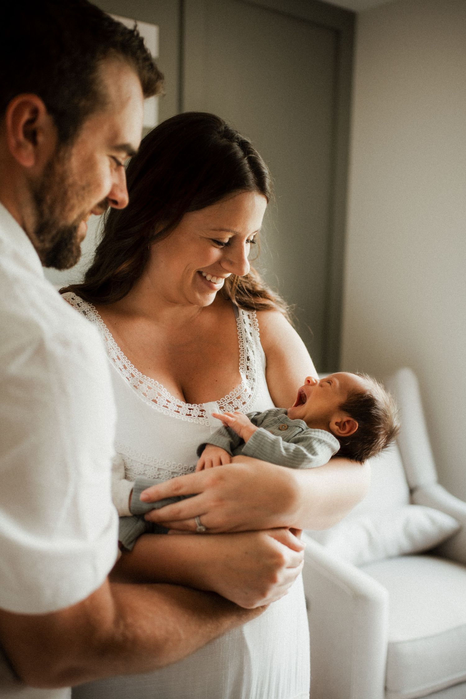 A tender series of intimate family moments showing parents cradling and bonding with their newborn baby in soft natural light.