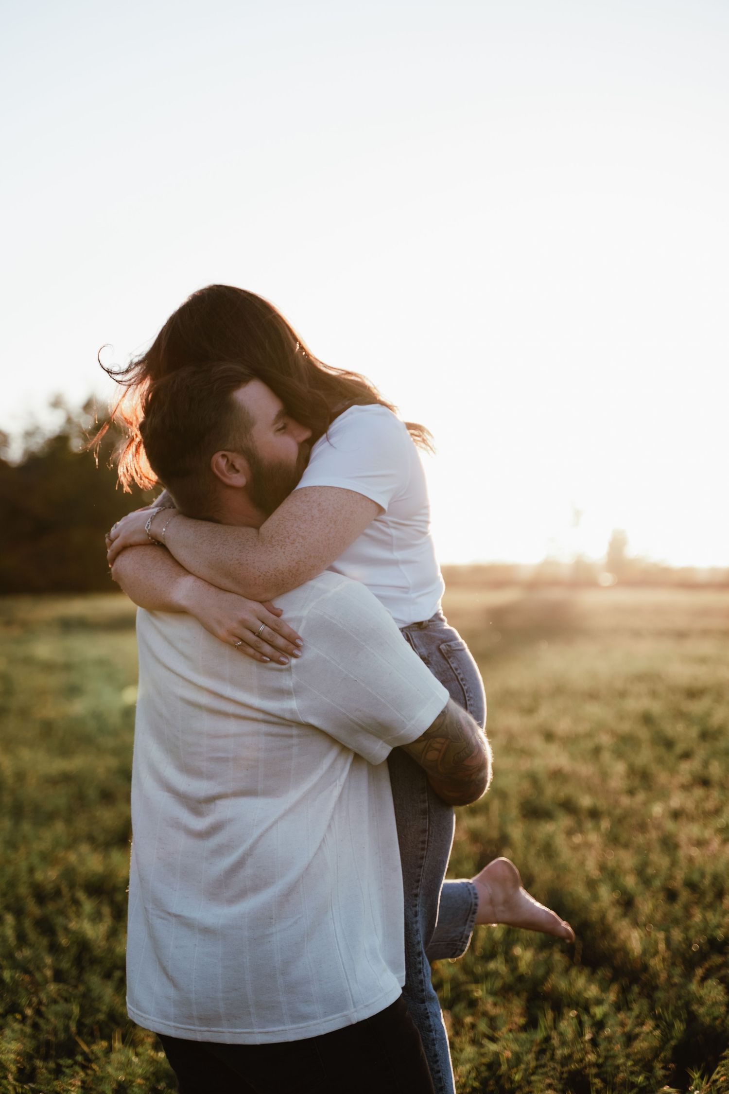 A couple embraces in a golden field at sunset creating a romantic silhouette against the warm sky.