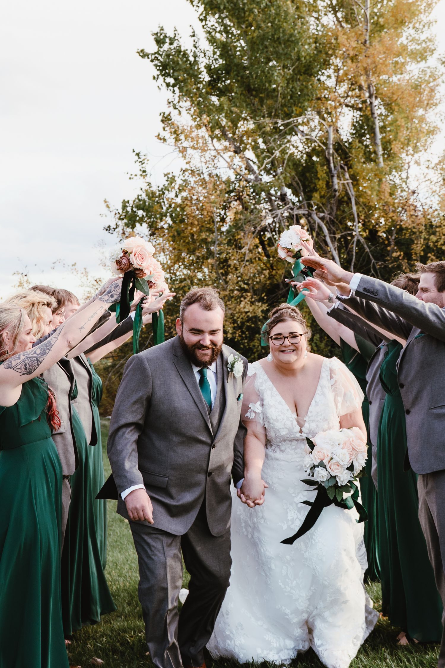 Wedding party celebrates outdoors with bride and groom as they run through a tunnel at Peterborough Golf and Country Club