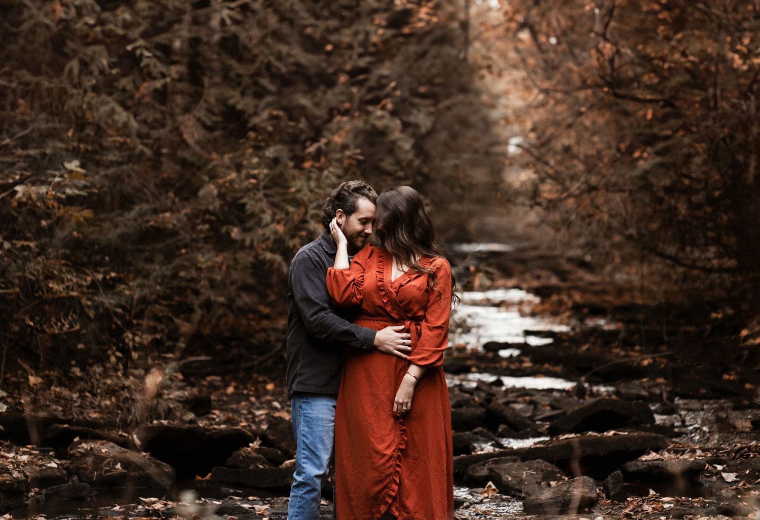 Romantic couple portrait series in autumn forest setting with rustic wooden pathway.