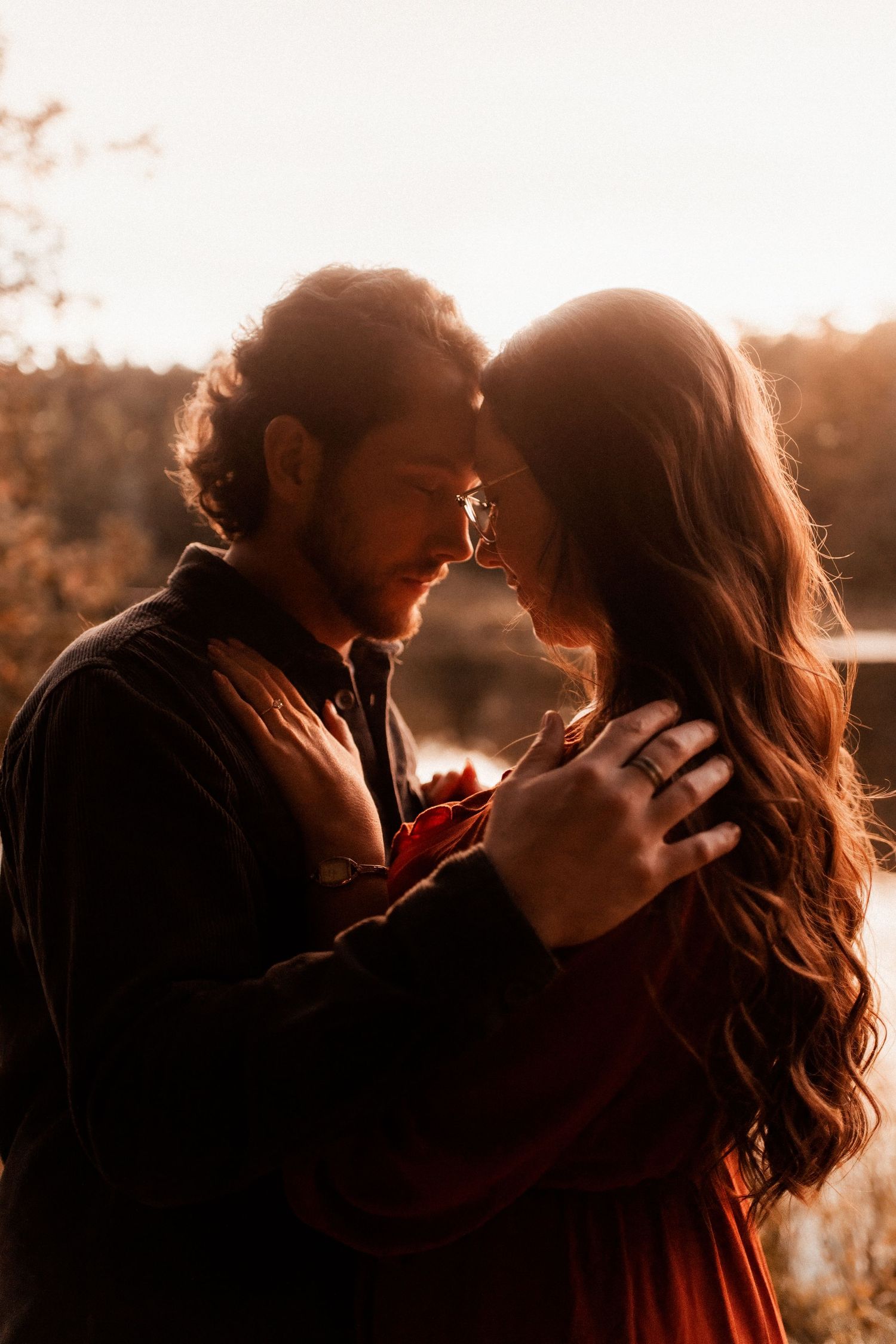 Backlit couple in tender embrace during golden sunset.