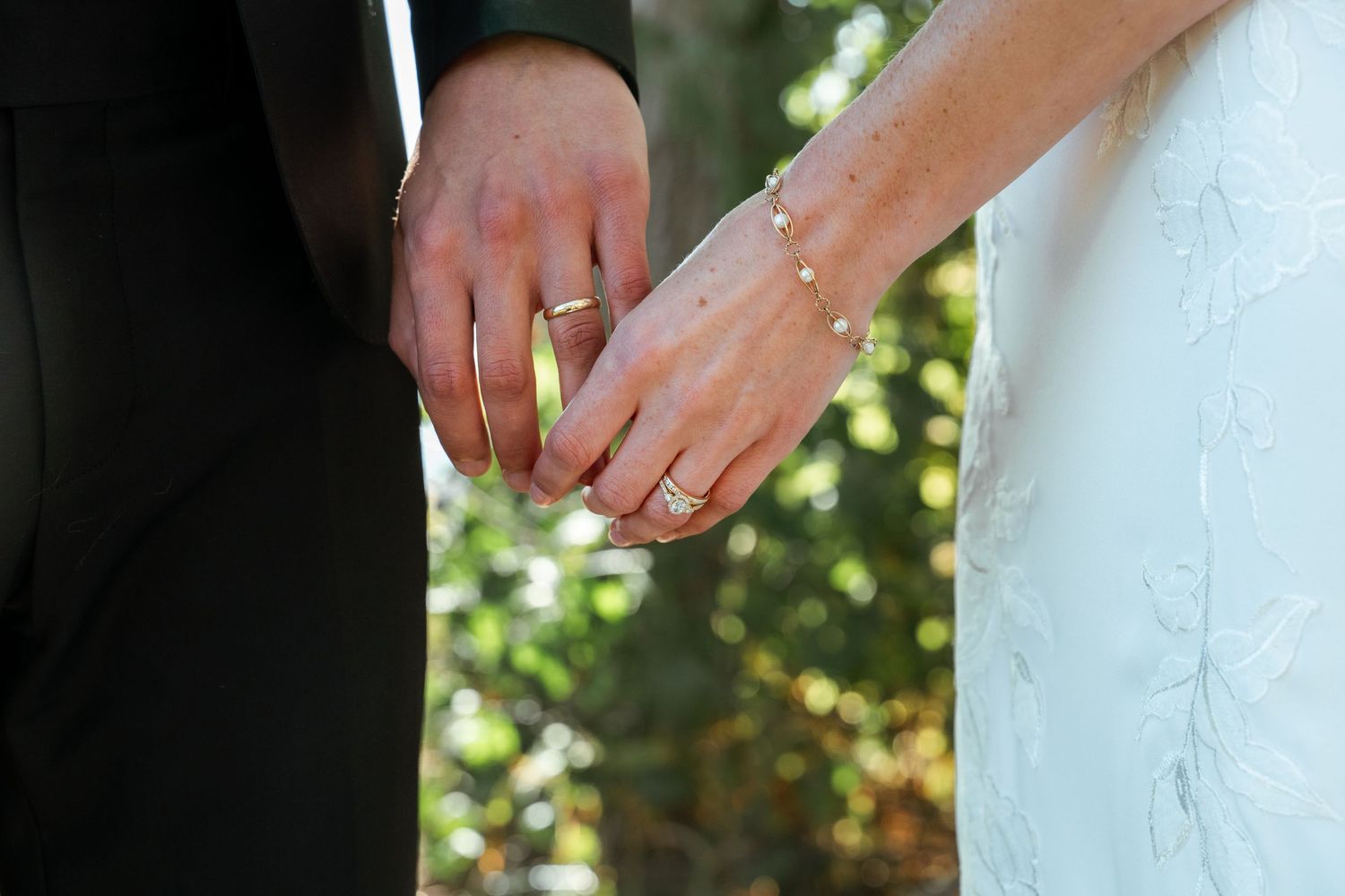 Close-up details of white wedding dress and hands during ceremony.