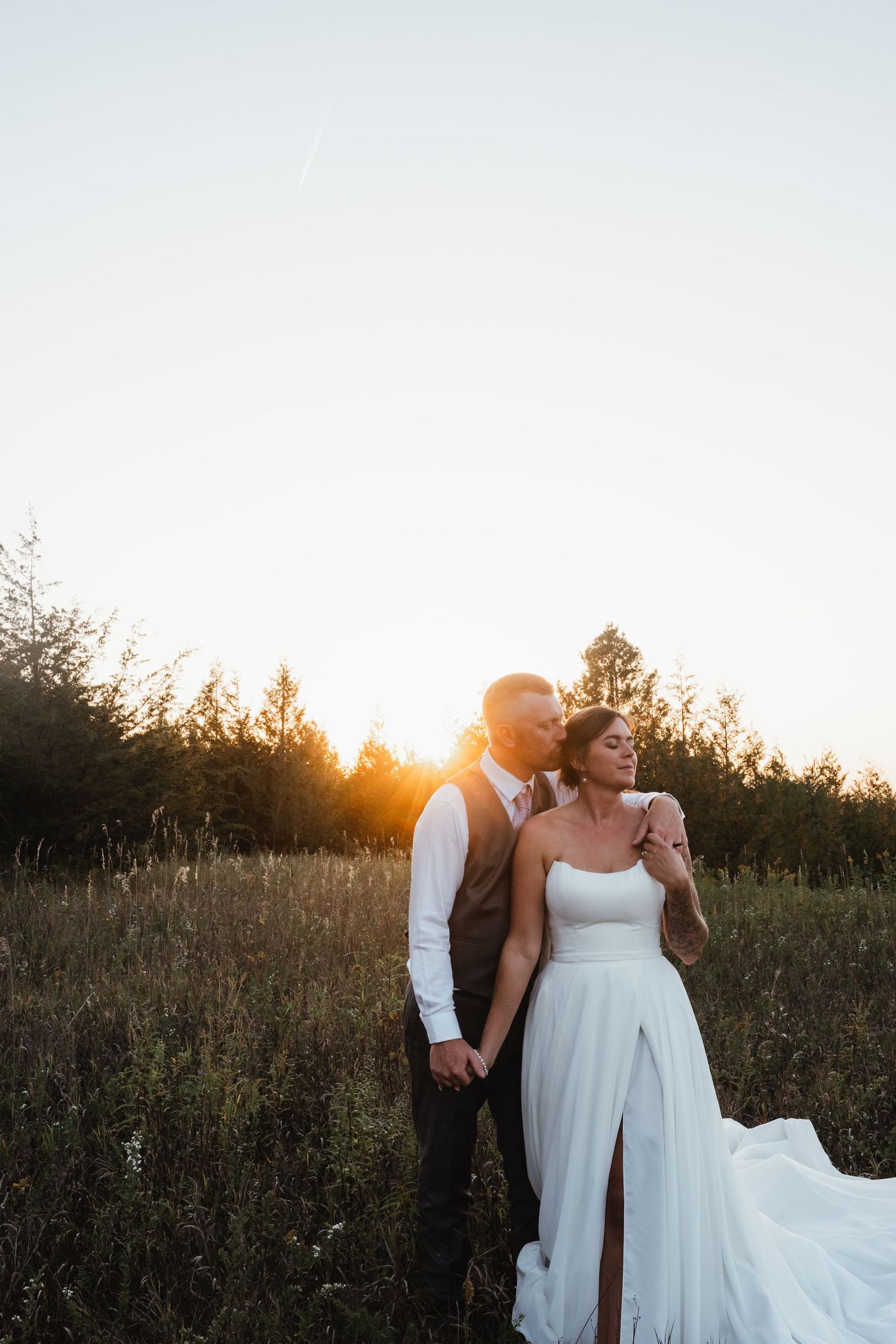 A romantic sunset wedding photo shoot in a golden field with flowing white dress and warm lighting.