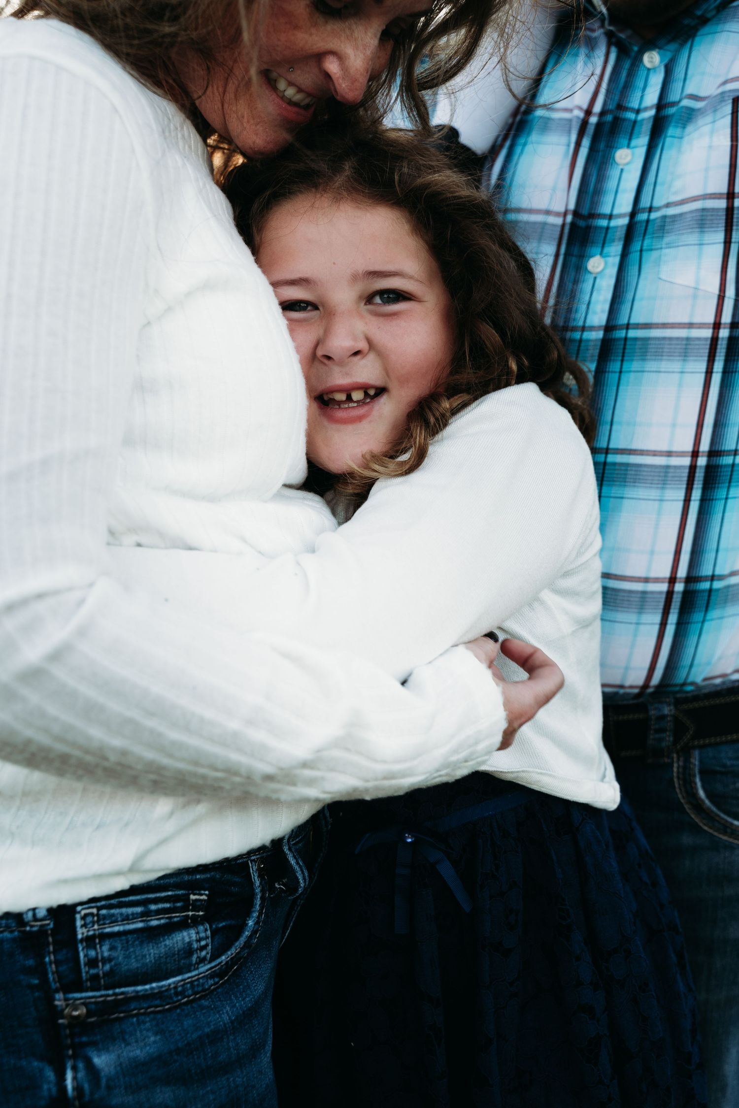 A heartwarming embrace shared between family members wearing white and plaid clothing.