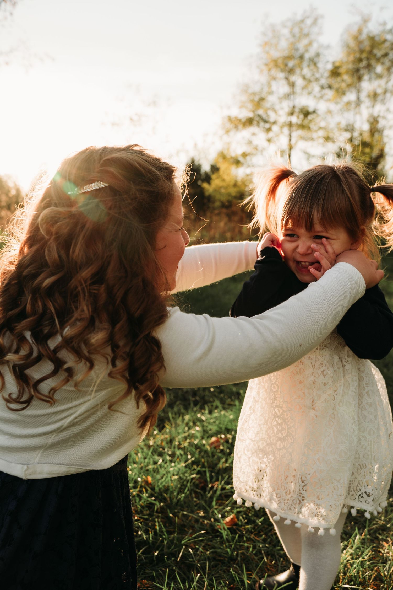 Two people share a joyful moment together outdoors in autumn sunlight.