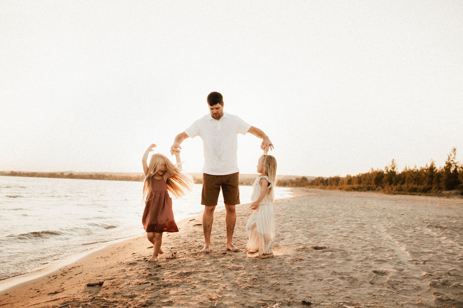 Family walking together along the shoreline during golden hour.