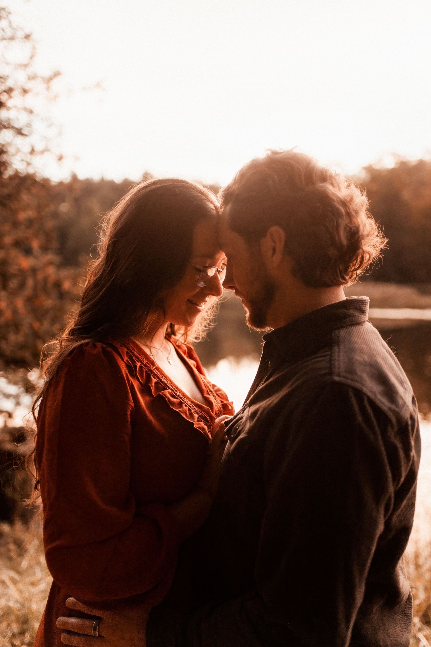 Silhouetted couple sharing intimate moment during golden hour sunset.