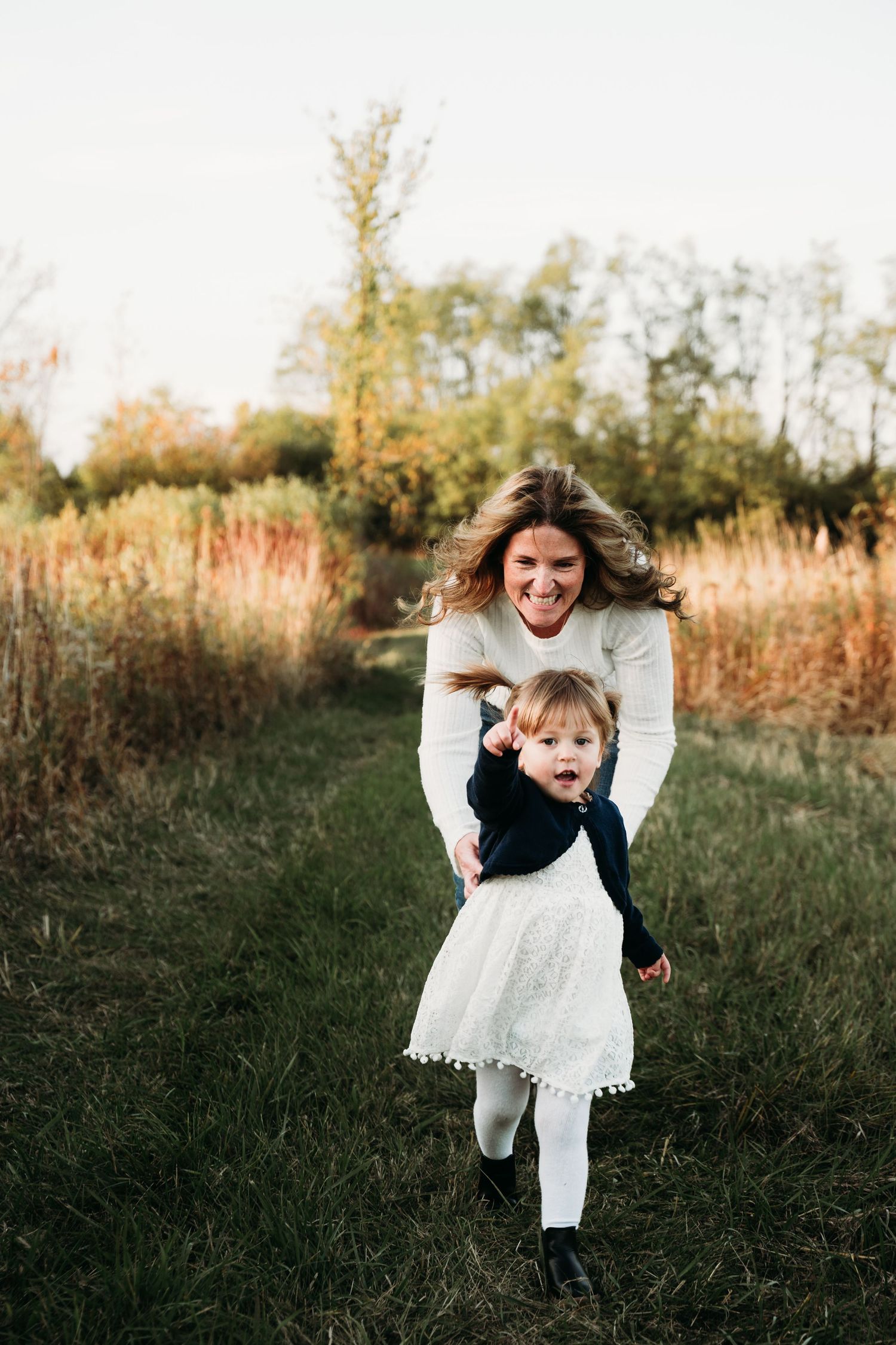 A playful chase through a grassy field during golden hour.