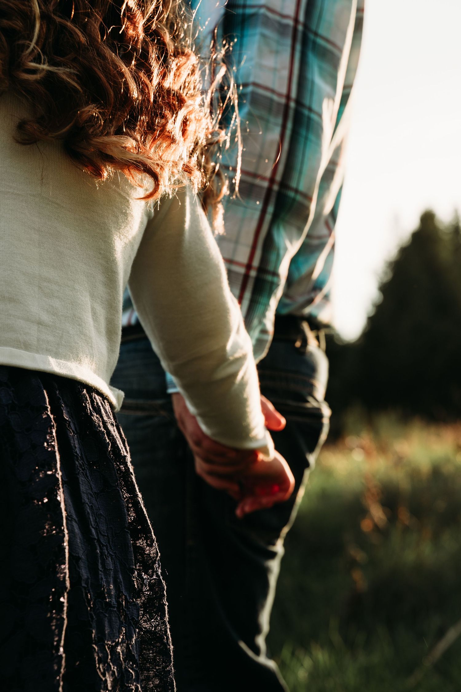 Close-up of hands holding while standing in a grassy field at sunset.