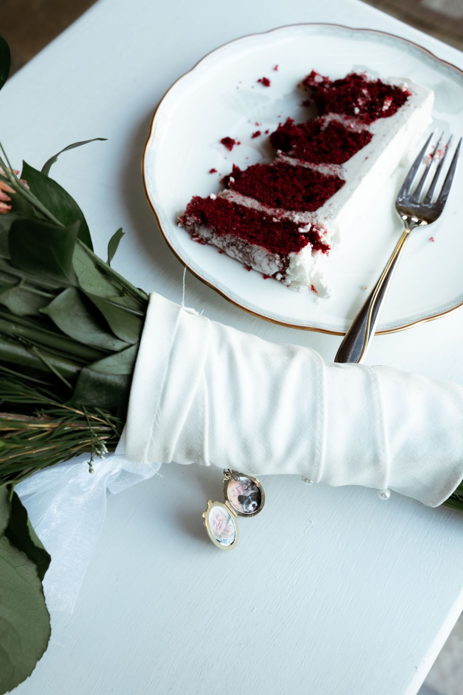 Red velvet cake remnants on white plate with silverware and table decor.