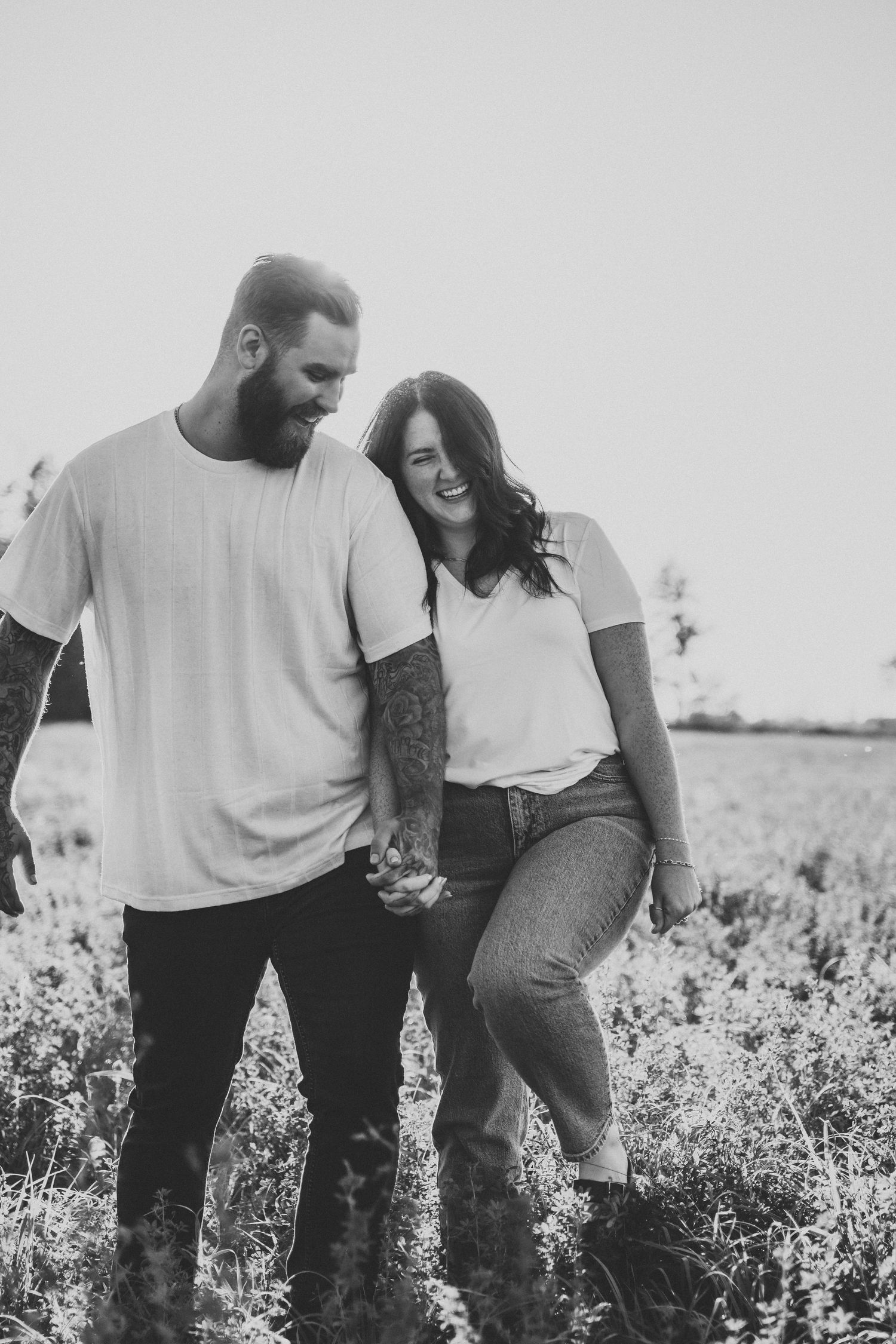 Couple in casual attire playfully interacting in a sunny field.
