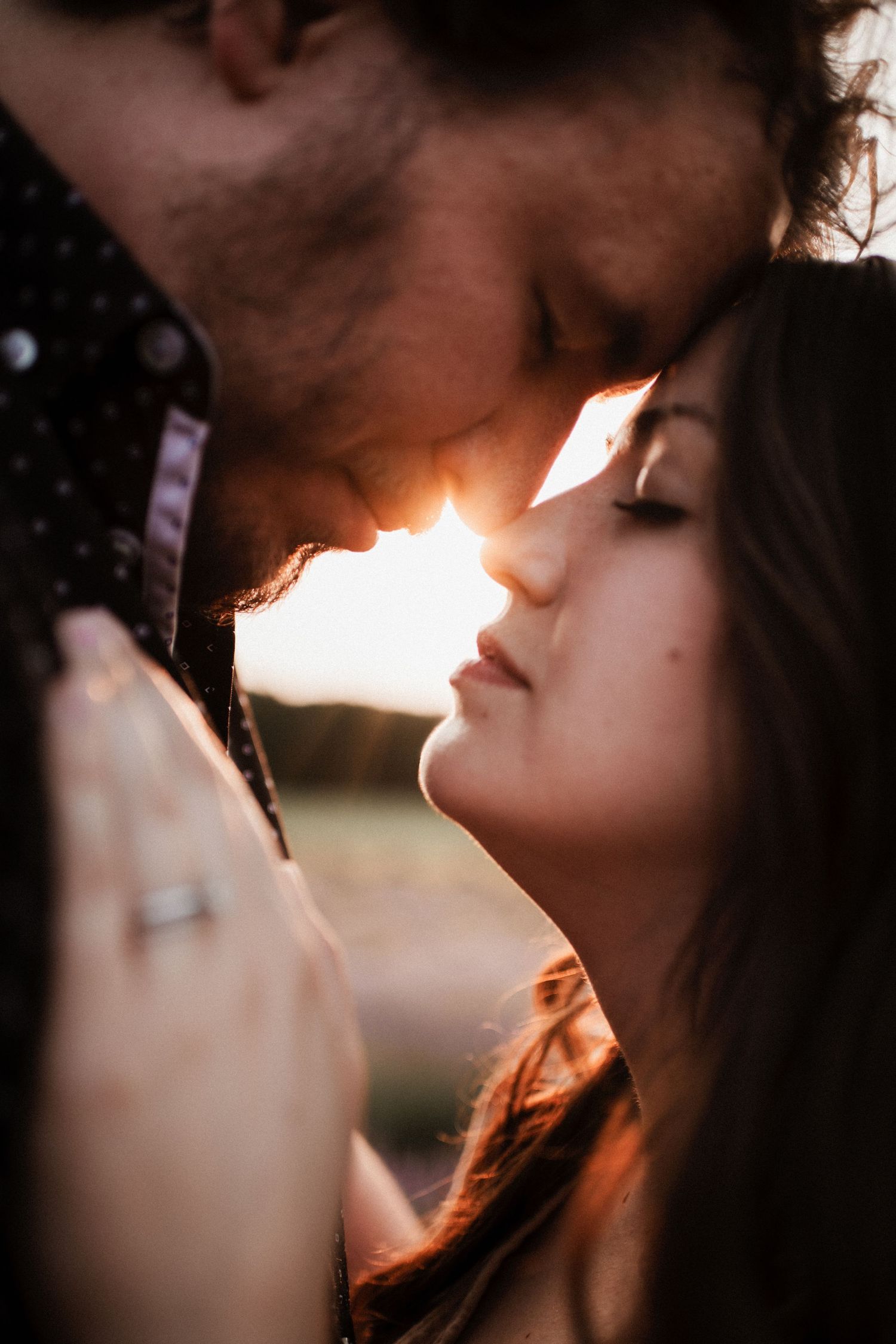 Atmospheric close-up portrait of couple in golden sunset light.
