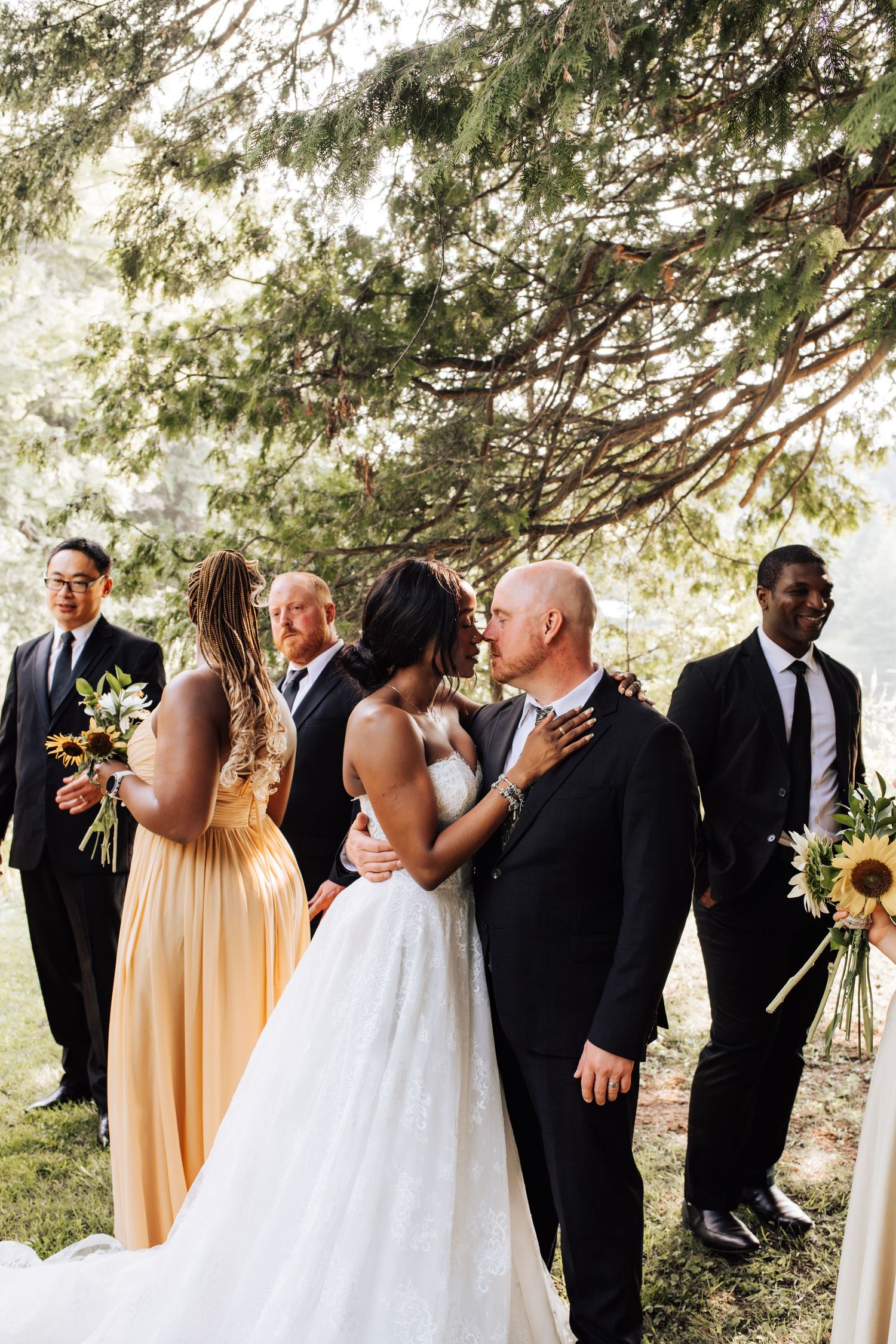 Wedding party in black and yellow attire poses under trees at O'Hara Mills Homestead