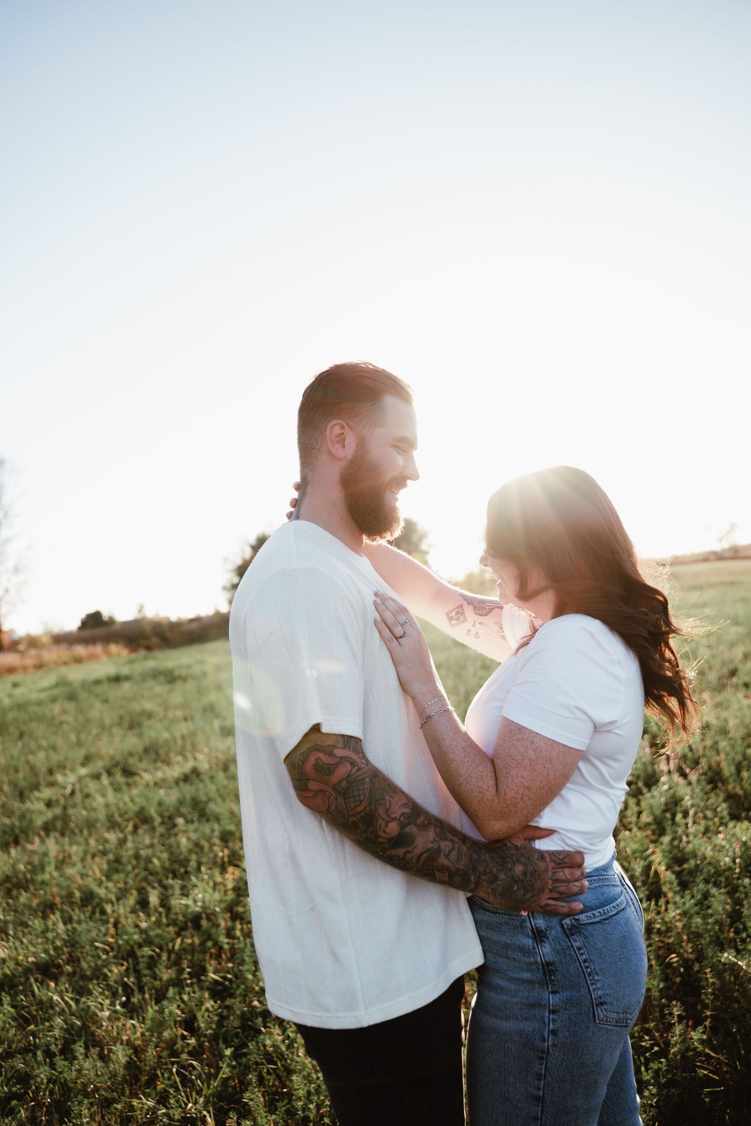 Romantic sunset portrait of couple embracing in a grassy field.
