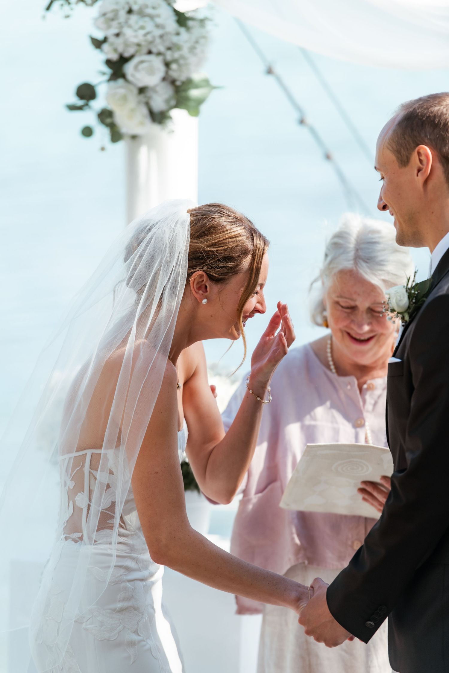 Wedding ceremony moment captured with white floral arrangements and delicate veil details.