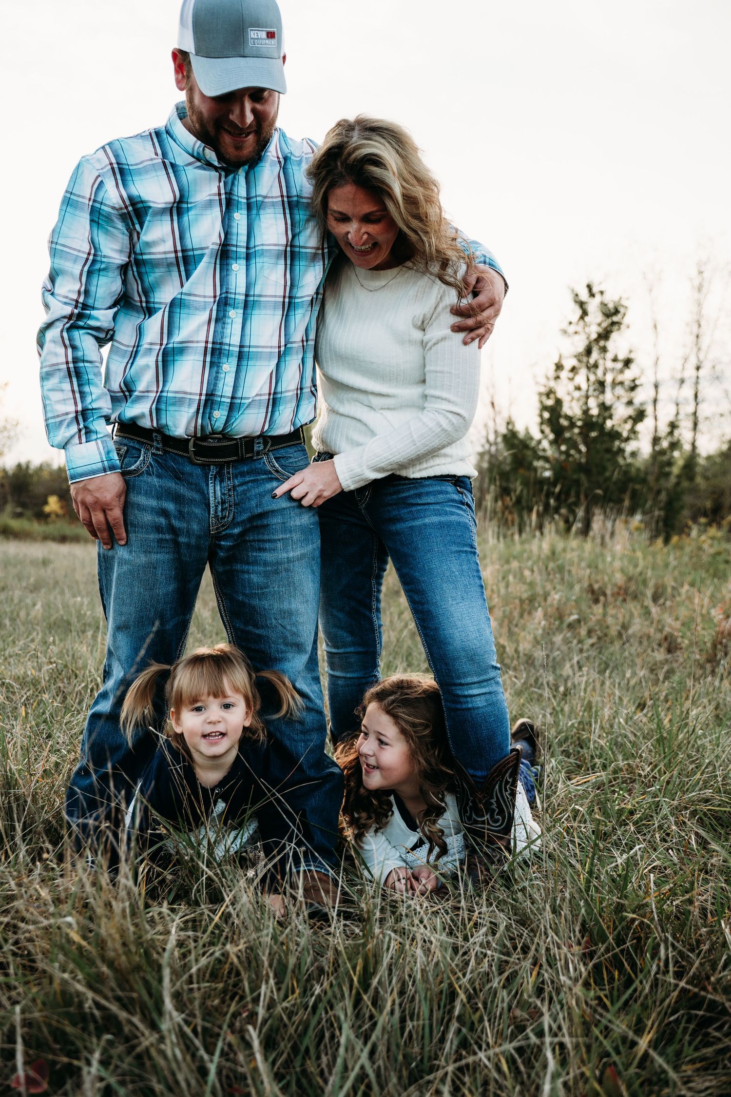 A family shares a playful moment together in a grassy field at sunset.