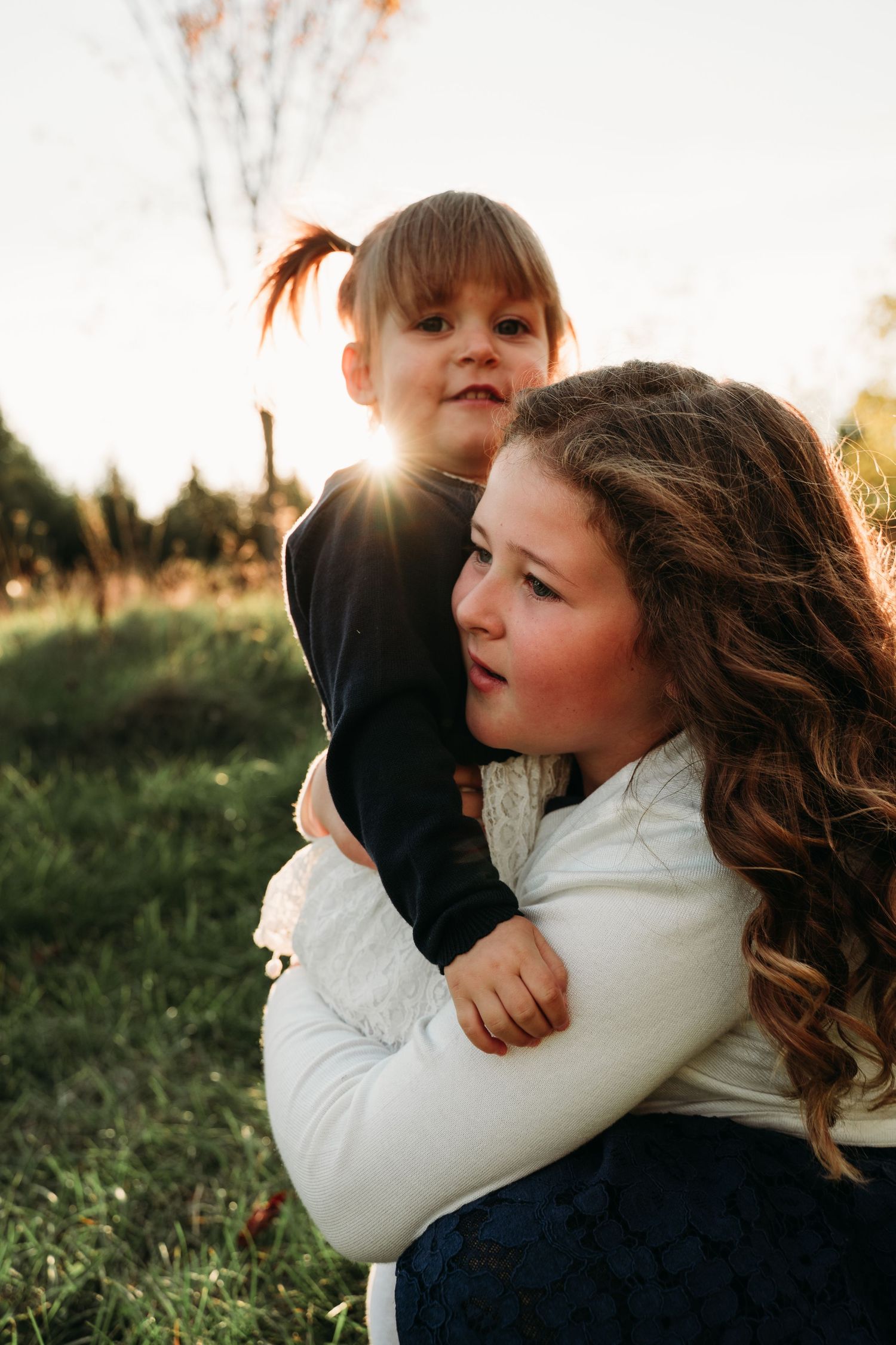 A tender moment between two people embracing in a sunlit field.