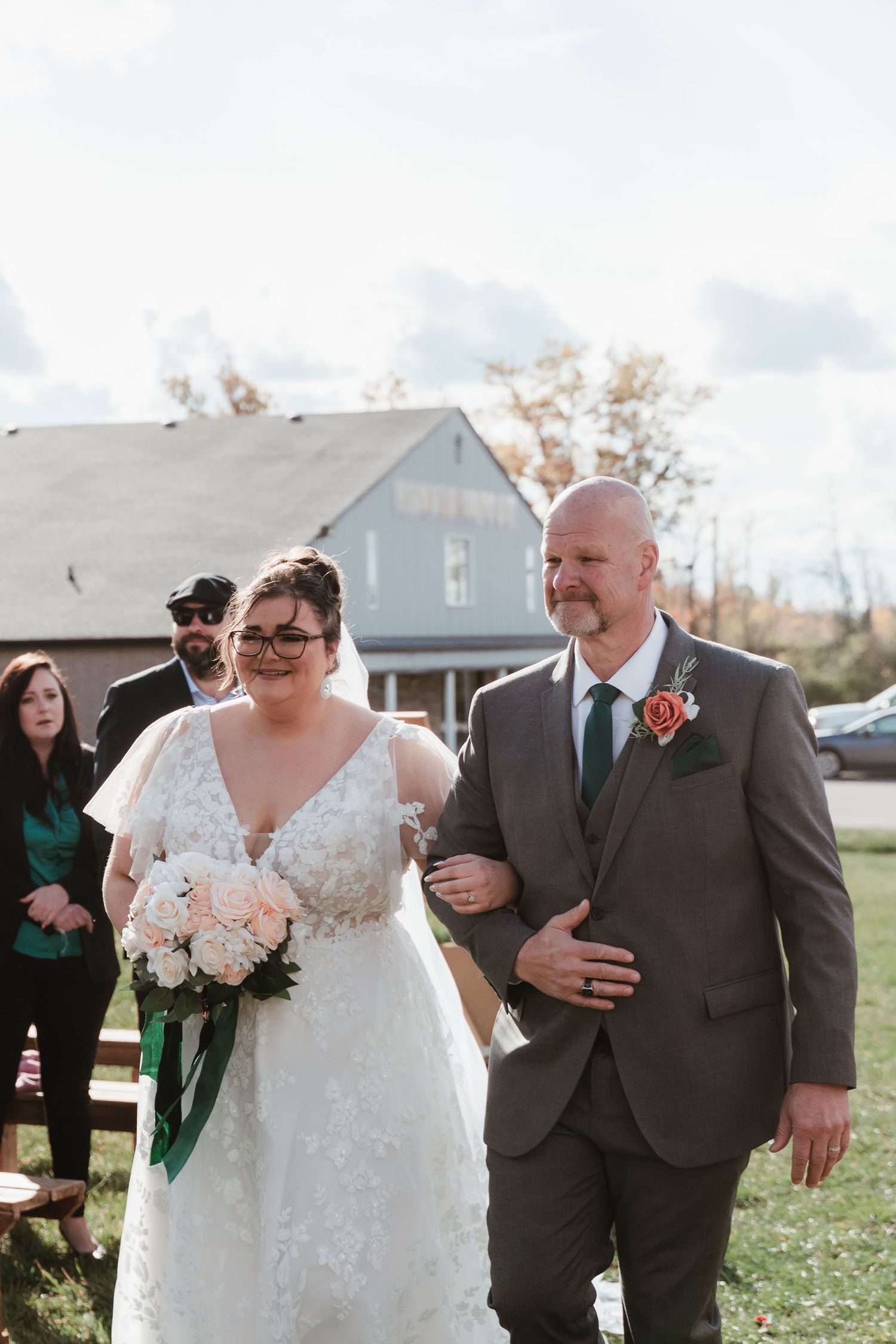 Wedding party walking outdoors in grey suits and white dress against residential backdrop.