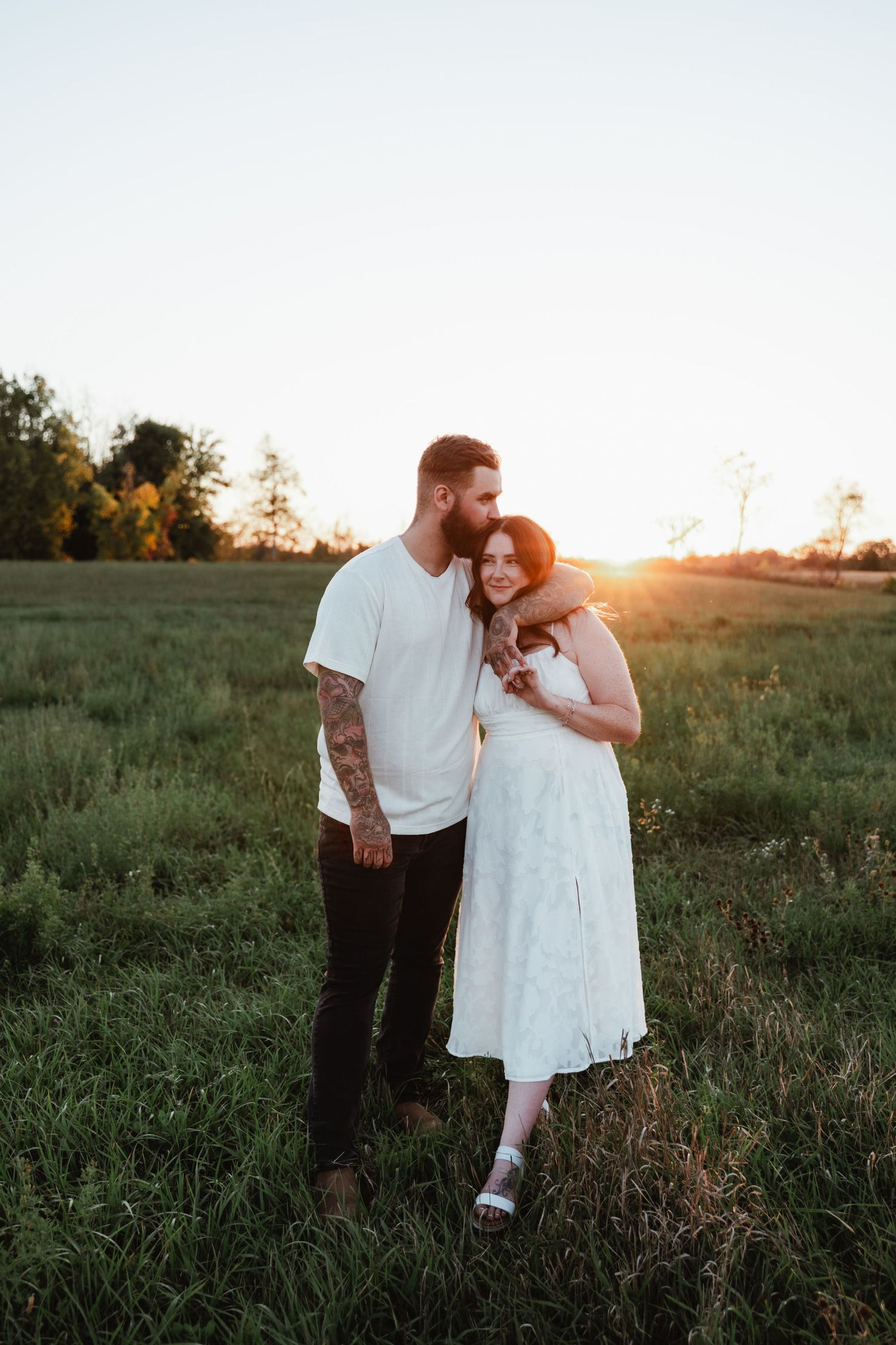 Intimate couple's portrait in rustic field during golden hour.