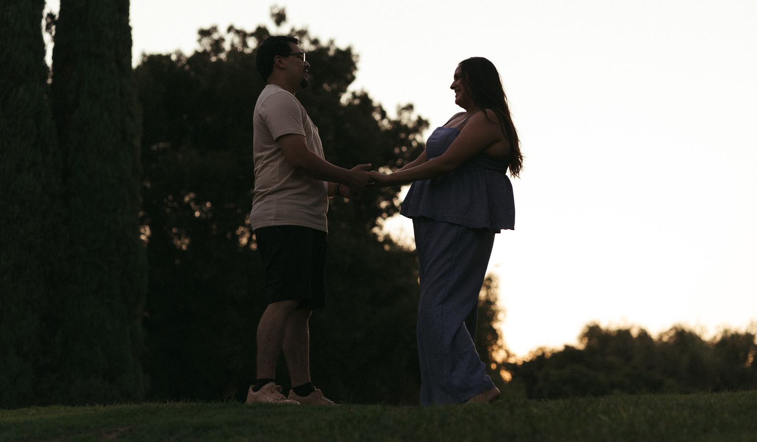 Couple holding hands at sunset during an engagement session in madera, California.