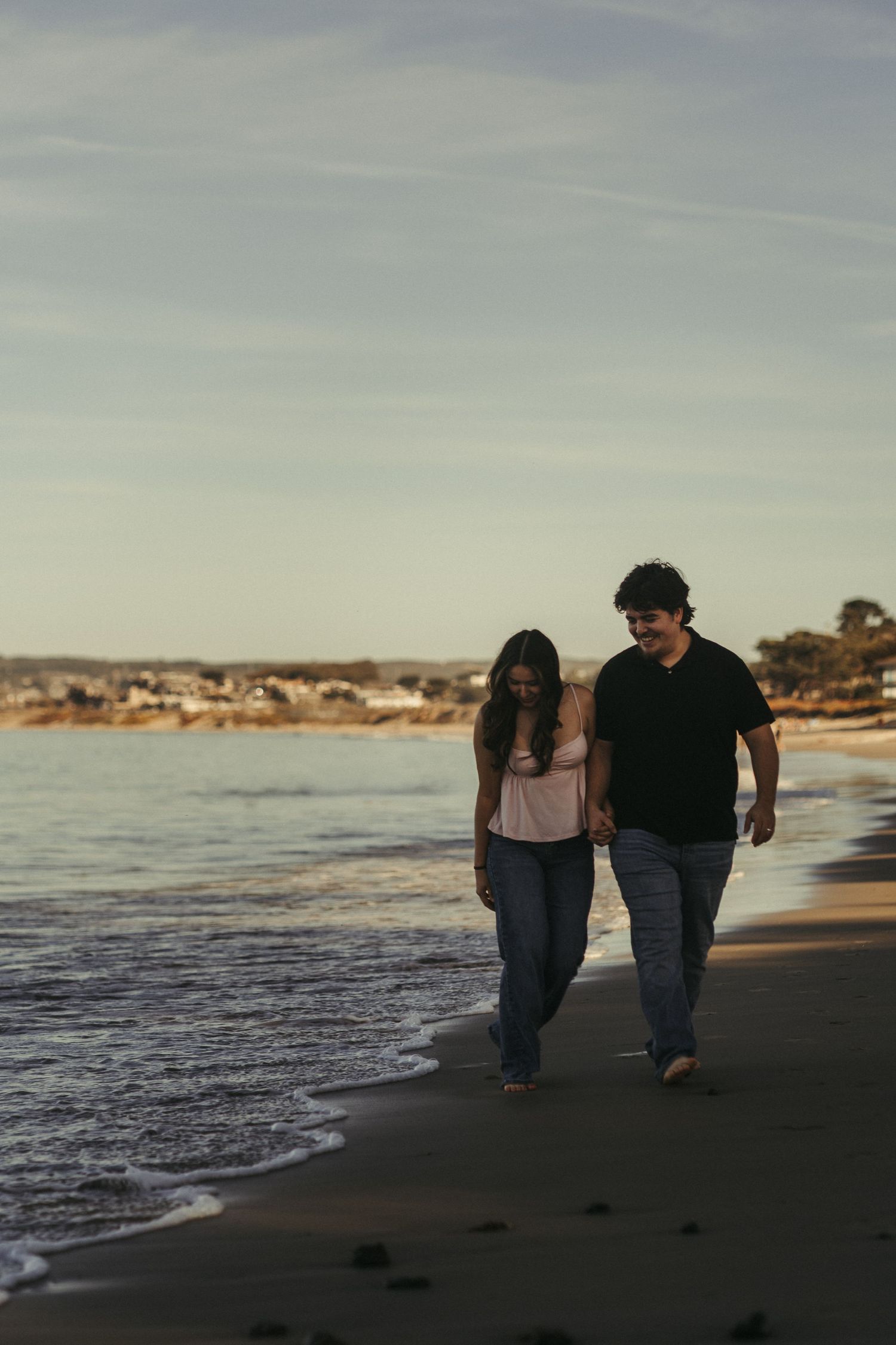 Couple walking through the beach water during their couple's photo session in Monterey