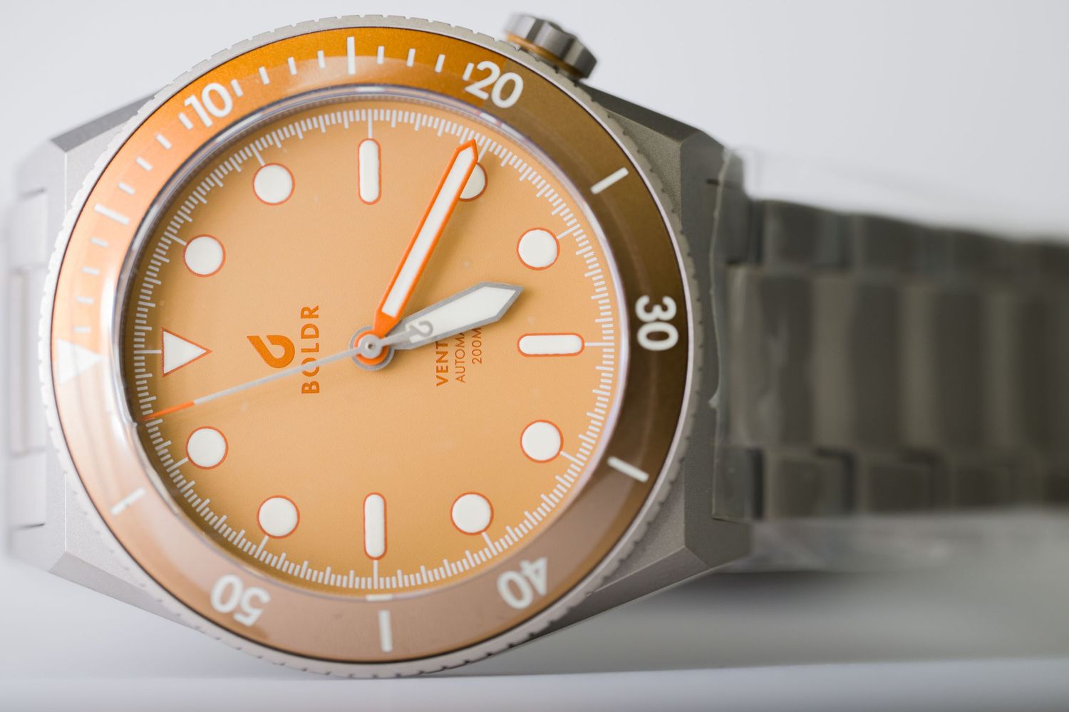 Orange dial Balor diver watch with stainless steel bracelet and rotating bezel displayed on white surface.