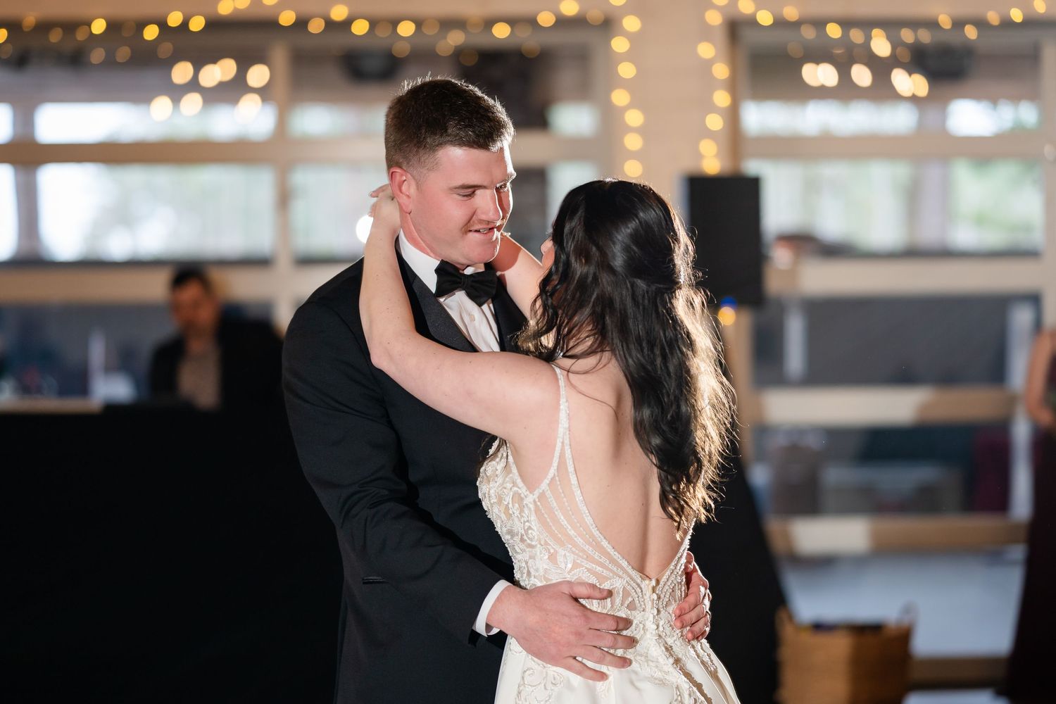 Bride and groom share a romantic first dance at a warmly lit wedding reception.