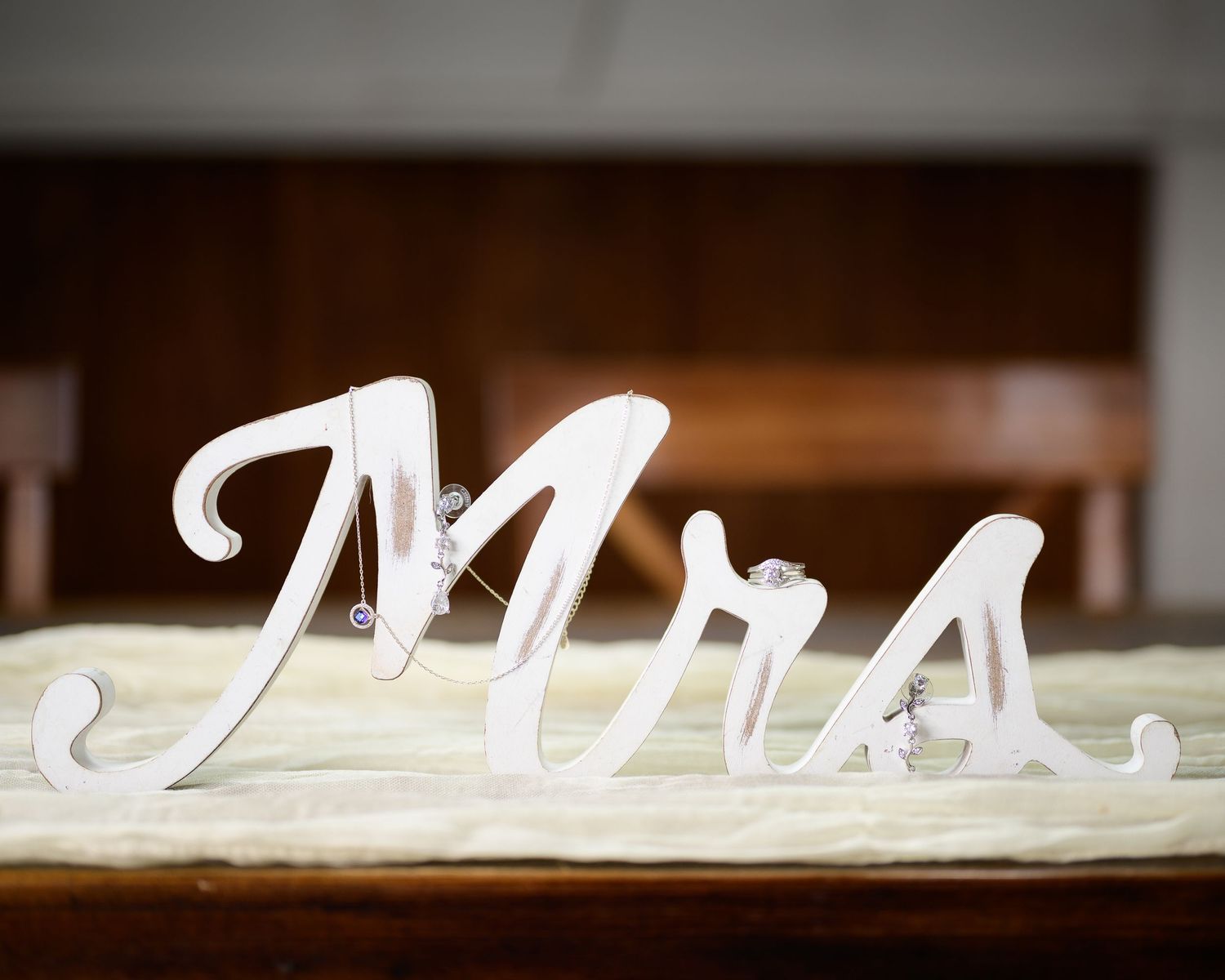Decorative white wooden Mrs. sign with rhinestone accents displayed on wedding reception table.